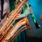 Musician playing saxophone on blurred background, melody music sound.