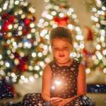 A little girl in a black dress with stars in a Christmas atmosphere. The girl is happy for Christmas. Christmas decorations.