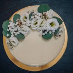 White cake decorated flowers and greenery for a banquet. Stylish wedding cake for newlyweds. Birthday cake with decor. Closeup
