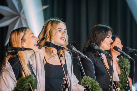Téléchargez les photos : Valmiera, Lettonie - 28 décembre 2023 - quatre femmes chantant dans des microphones, se produisant probablement dans un chœur ou un groupe. - en image libre de droit