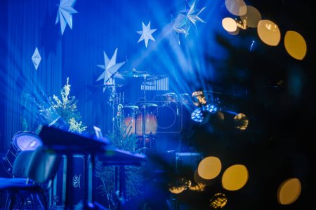 Foto de Valmiera, Letonia - 28 de diciembre de 2023 - escenario con instrumentos de percusión, un árbol de Navidad y estrellas decorativas iluminadas por la iluminación azul del escenario - Imagen libre de derechos