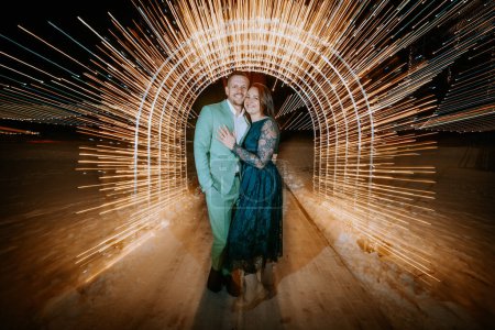 Foto de Una pareja abrazándose en un túnel de senderos de luz dinámicos con un suelo nevado debajo de ellos. - Imagen libre de derechos