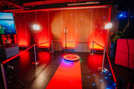 360 Spinner Fotokabinen-Aufbau mit rotem Teppich und Beleuchtung an einem Veranstaltungsort mit roter Ambientebeleuchtung.