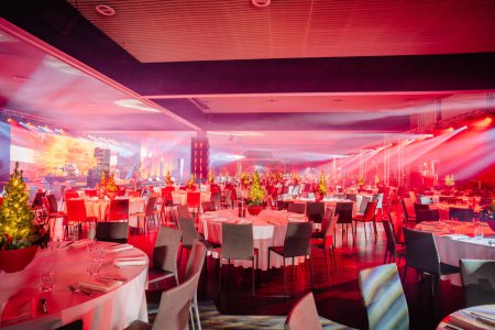 festively decorated banquet hall with tables, Christmas trees, and vibrant red and blue lighting