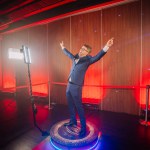 Riga, Latvia - December 18, 2023 - person standing on a 360-degree photo booth platform, often referred to as a 360 spinner, used for capturing dynamic, panoramic video content at events.