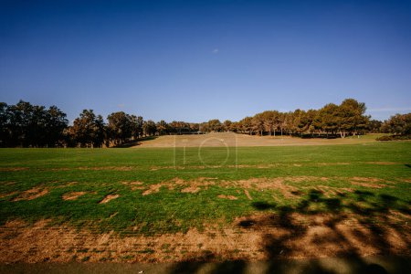 Foto de Málaga, España - 21 de enero de 2024 - Una vista al campo de golf con parches de hierba verde, árboles y un cielo azul. - Imagen libre de derechos