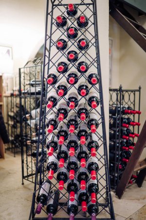 Photo for Sotogrande, Spain - January, 23, 2024 -  tall wine rack filled with bottles in a diagonal pattern, set in an indoor space with more racks in the background. - Royalty Free Image