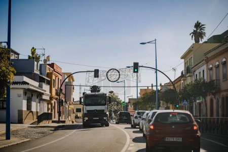 Foto de Santa Margarita, España - 24 de enero de 2024 - calle con vehículos, arcos decorativos, semáforos encendidos y edificios en contra de un cielo despejado - Imagen libre de derechos