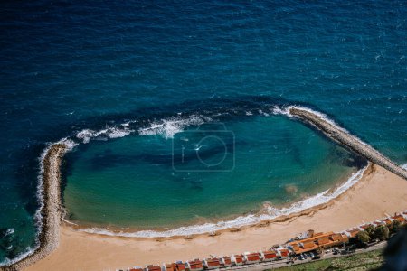 Photo for Gibraltar, Britain - January 24, 2024 - Aerial view of a sandy beach enclosed by breakwaters with waves and clear blue sea. - Royalty Free Image
