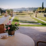 Sotogrante, Spain - January 26, 2024 -  table with a vase of pink roses overlooking a landscaped garden and golf course.