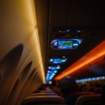 Riga, Latvia - January 28, 2024 - Airplane cabin interior with dim lighting, overhead monitors displaying map, passengers seated.