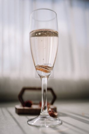 Foto de Valmiera, Letonia - 7 de julio de 2023 - Un primer plano de una flauta de champán con dos anillos de boda sumergidos en líquido brillante, con un fondo borroso. - Imagen libre de derechos