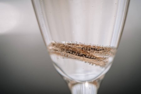 Valmiera, Latvia - July 7, 2023 - Close-up of a glass with sparkling wine and two wedding rings creating bubbles.
