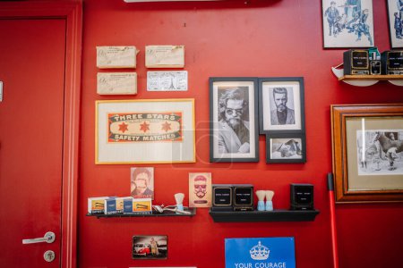 Téléchargez les photos : Valmiera, Lettonie - 7 juillet 2023 - Un mur rouge décoré d'œuvres d'art vintage liées au coiffeur, de photos encadrées, de boîtes d'allumettes et de produits de toilettage. - en image libre de droit