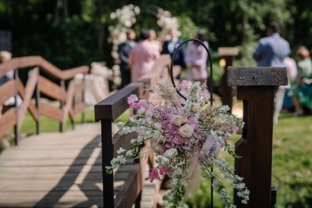 Valmiera, Lettonie - 7 juillet 2023 - Arrangement floral sur une rampe de pont avec des invités en arrière-plan.