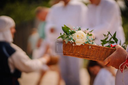 Jurmala, Latvia - july 25, 2023 - Close-up of a hand holding a woven basket with flowers and leaves.