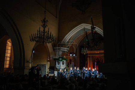 Photo for Valmiera, Latvia - January 7, 2024 - Saint Simon's Church. Choir performing in a church illuminated by a chandelier and natural light from a window, audience in foreground. - Royalty Free Image