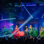 Valmiera, Latvia- February 15, 2024 - A traditional gypsy concert with four female performers in colorful dresses, one singing and three dancing, and a drummer in the background.