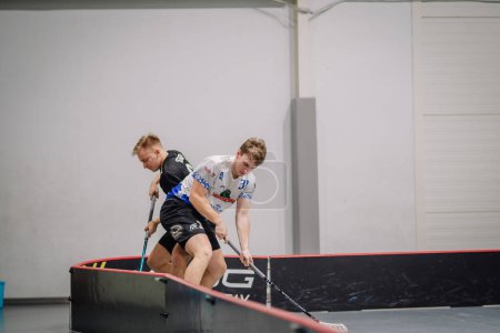Photo for Valmiera, Latvia - February 17, 2024 - two floorball players competing for the ball; one is pushing against the other near the rink's edge. - Royalty Free Image
