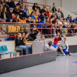 Valmiera, Latvia - February 17, 2024 -  a floorball player falling near the rink boards with spectators in the stands visibly reacting to the game