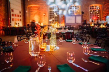 Foto de Riga, Letonia - 16 de febrero de 2024 - una sala de banquetes cálidamente iluminada con mesas preparadas para un evento, con centros de mesa brillantes y paredes de ladrillo - Imagen libre de derechos