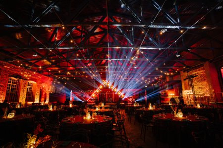 Riga, Latvia - February 16, 2024 - an event space with a vibrant light show, red ambient lighting, and tables set for a festive occasion.