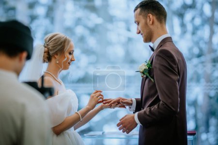 Riga, Lettonie - 20 janvier 2024 - Une jeune mariée échange des alliances lors d'une cérémonie de mariage avec une toile de fond enneigée.