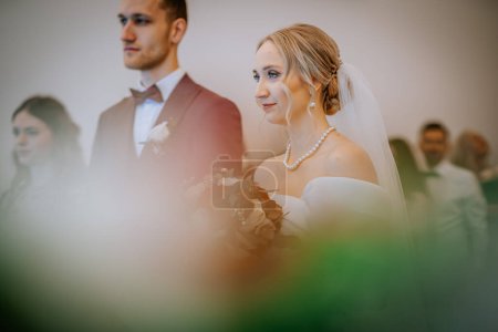 Riga, Lettland - 20. Januar 2024 - Bei einer Hochzeit stehen Braut und Bräutigam in formeller Kleidung im Mittelpunkt, während andere im Hintergrund verschwimmen.