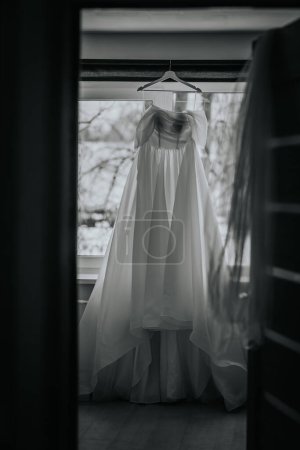 Riga, Latvia - January 20, 2024 - A wedding dress hanging in a window-lit room.
