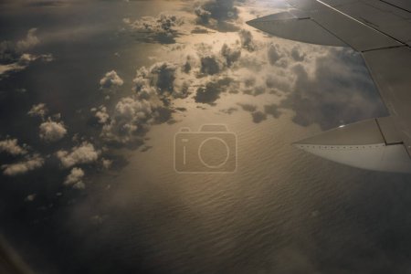 Agadir, Morocco - February 24, 2024 - Aerial view of clouds and ocean from an airplane window at sunset.