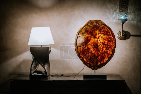 Agadir, Morocco - February 25, 2024 - Two illuminated objects, a table lamp with a white shade on the left and a vibrant, round amber light fixture on the right
