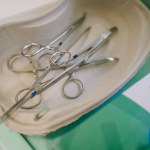 Valmiera, Latvia - March 20, 2024 - A tray with sterilized surgical instruments, including scissors and forceps, alongside a box of gloves, suggests a medical procedure is imminent.