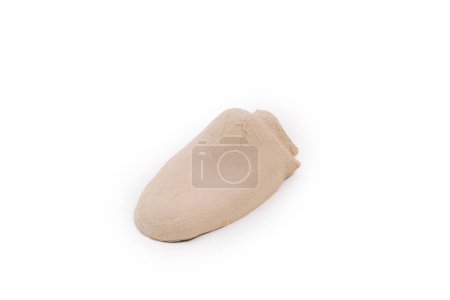 Ein beigefarbener brotförmiger Gegenstand, die Innenform eines Pappschuhs, um die Form des Schuhs nicht zu verlieren, auf weißem Hintergrund.