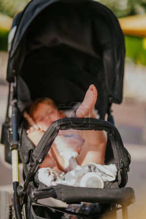 Dubai, Vereinigte Arabische Emirate - 19. Oktober 2019 - Die Füße eines Babys ragen aus einem Kinderwagen, eine Flasche ist zu sehen, die auf ein entspanntes oder schlafendes Kind hinweist..