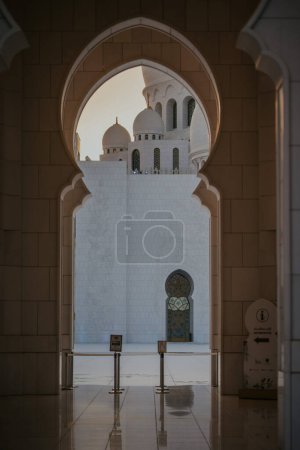 Dubai,  Unite dArab Emirates - October 19, 2019 - Archway framing a view of domes and a minaret of a mosque against a clear sky.