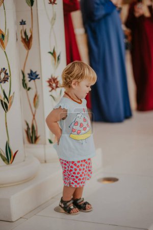 Dubai,  Unite dArab Emirates - October 19, 2019 - Toddler in a cute outfit with a pizza slice print, standing solemnly by a decorated column.