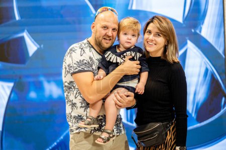 Dubai, Emiratos Árabes Unidos - 19 de octubre de 2019 - Un retrato familiar con un hombre, una mujer y un niño sonriendo a la cámara, con un patrón geométrico azul en el fondo.