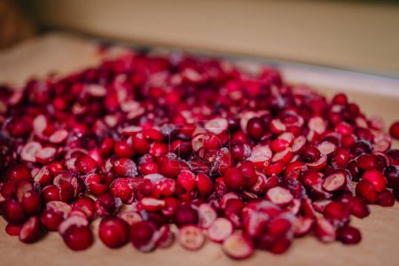 Close-up of a heap of sliced, freeze-dried cranberries with visible ice crystals on a cutting board.