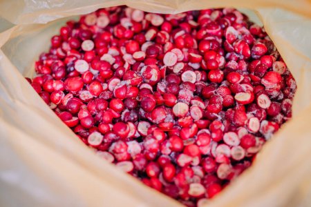Close-up of a bag full of crimson freeze-dried cranberries, some sliced, with visible frost particles.