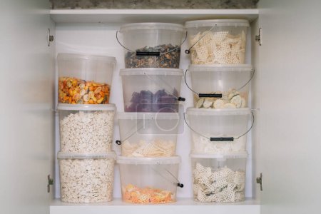 A pantry shelf with clear containers of various freeze-dried fruits and snacks.