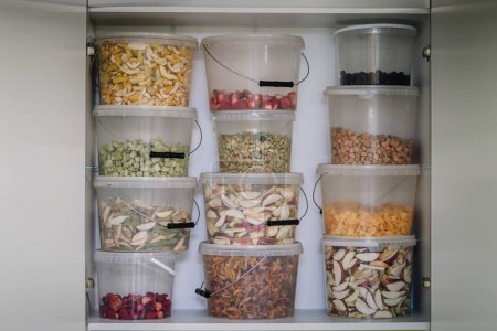 Téléchargez les photos : Une étagère de garde-manger garnie de contenants transparents remplis de divers fruits et légumes déshydratés. - en image libre de droit