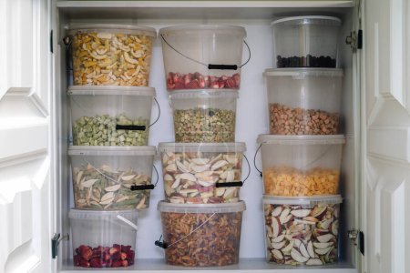 Téléchargez les photos : Une étagère de garde-manger garnie de contenants transparents remplis de divers fruits et légumes déshydratés. - en image libre de droit