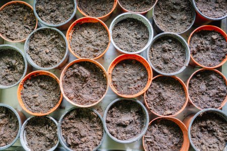 Top view of multiple empty pots filled with soil, arranged closely together.