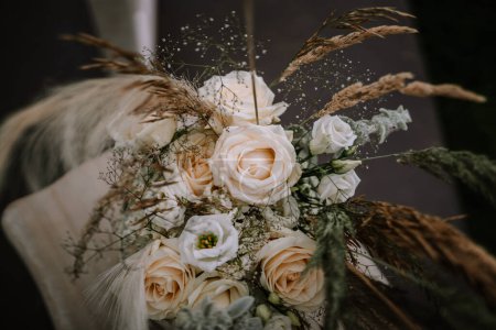 A close-up of a bridal bouquet featuring cream roses, pampas grass, and delicate filler flowers, creating a soft, natural, and textured appearance.