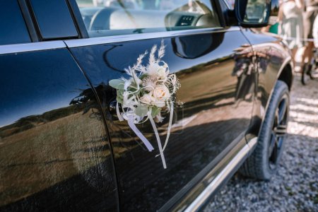 Valmiera, Lettland - 13. August 2023 - Ein Blumenschmuck an der Tür eines dunklen Autos, möglicherweise für eine Hochzeit.