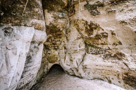 Valmiera, Lettland - 14. Juli 2023 - ein Höhleneingang mit Graffiti an den Wänden, der von sandigem Boden umgeben und mit natürlichen Strukturen und Markierungen bedeckt ist. Sietiniezis