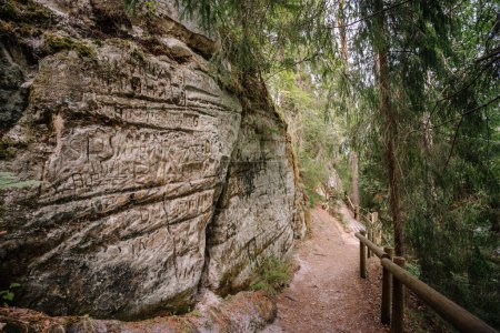 Valmiera, Lettland - 14. Juli 2023 - ein Waldweg entlang einer Sandsteinklippe mit eingeätzten Inschriften und Graffiti führt durch den Gauja Nationalpark, Lettland, bekannt als Sietiniezis.
