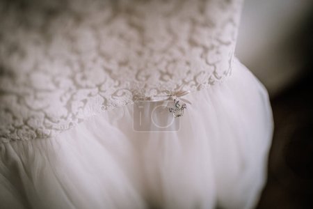 Photo for Valmiera, Latvia- July 28, 2024 - A close-up of a white bridal dress with lace detailing and a delicate charm attached to the waistband, capturing the intricate details and soft texture. - Royalty Free Image