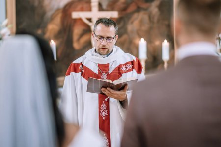 Valmiera, Lettland - 28. Juli 2024 - Ein Priester in liturgischen Gewändern liest während einer Zeremonie aus einem Buch.