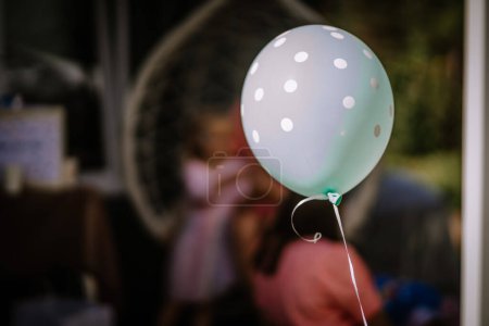 Valmiera, Lettland - 29. Juli 2023 - Ein gepunkteter Luftballon ist im Fokus mit einer verschwommenen Figur im Hintergrund, möglicherweise auf einer Party oder Feier.